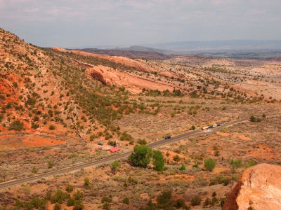 [The road into the park cuts a diagonal across the land as the ground begins to swell to create the canyon walls.]